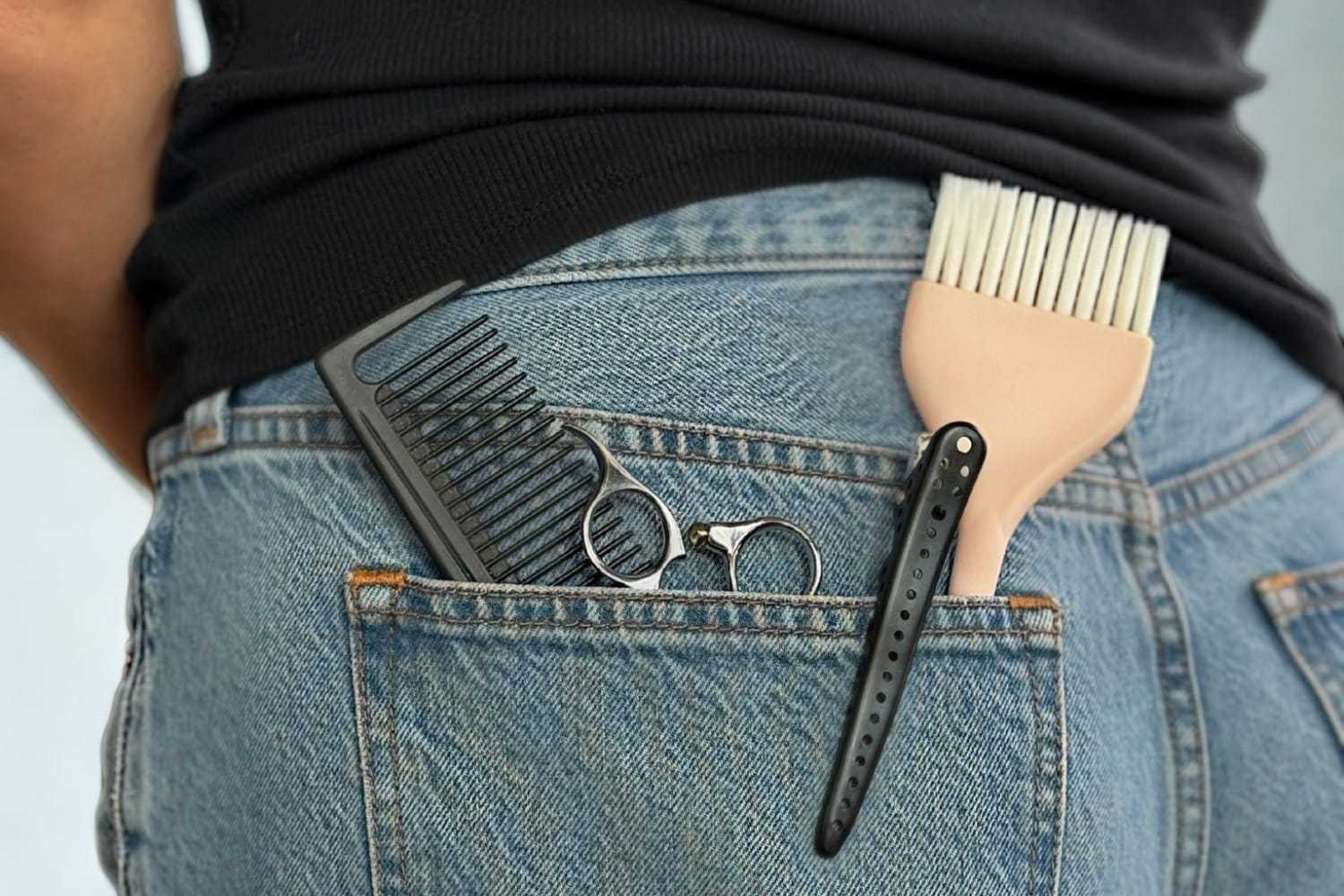 Combs and scissors in back pocket of blue jeans.